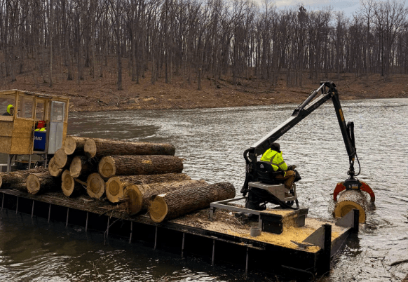 MTM barge handling cut timber near a shoreline